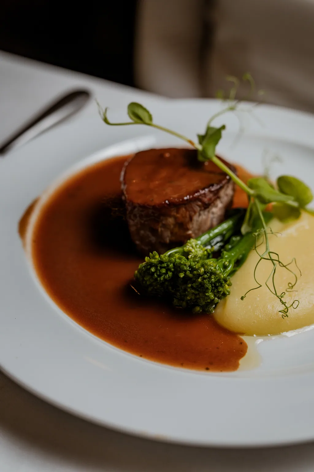 Tornedó com molho bordelaise, puré de aipo e maçã e brócolos, em prato branco