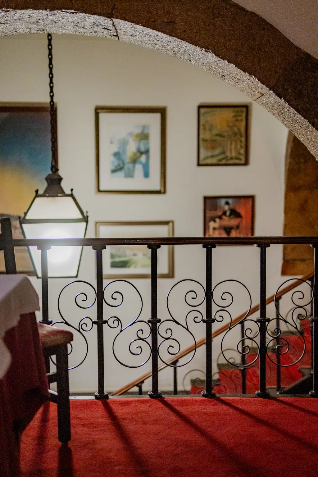 Escadaria de ferro forjado com os quadros e o candeeiro